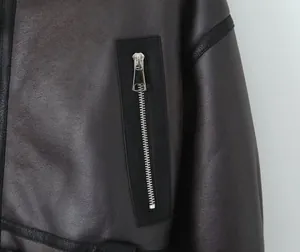 Gros plan d'une fermeture éclair argentée sur une veste en similicuir marron avec fourrure.
