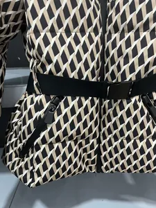 Close-up detail of geometric pattern puffer jacket with black waist belt and zipper