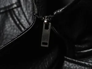 Macro view of the high-quality metal zipper detail on a black leather biker jacket.