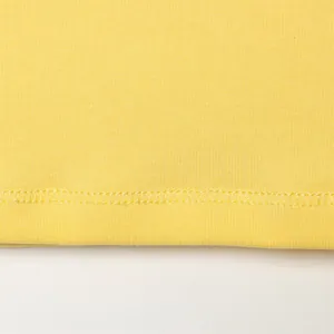 Vista macro de la costura fina y la suave tela de algodón amarillo de una camiseta