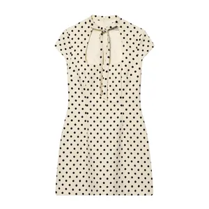 Vue détaillée d'une robe courte à pois crème avec un décolleté découpé et un nœud élégant