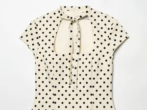 Détail d'une robe crème à pois avec un élégant nœud et une découpe