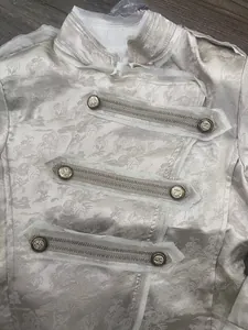 Detail eines elfenbeinfarbenen Jacquard-Blazers mit Stehkragen und Militärknopf-Verzierung.