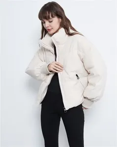 Woman wearing a cream-colored loose-fitting puffer jacket in a studio setting.