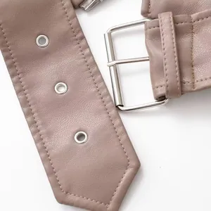 Gros plan sur une ceinture en similicuir mauve avec boucle en argent et œillets