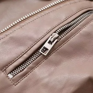 Gros plan d'une fermeture éclair en métal argenté sur une veste de motard en cuir taupe