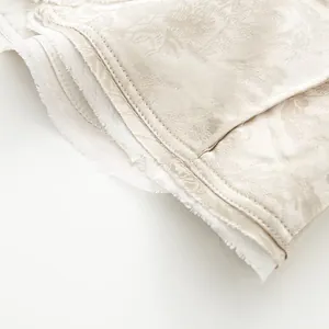 Makro-Detail von elegantem beigem Jacquard-Blumenstoff und Nähten an einer Anzugjacke