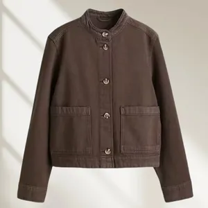 Detail van een bruin twill spijkerjasje met opstaande kraag en opgestikte zakken