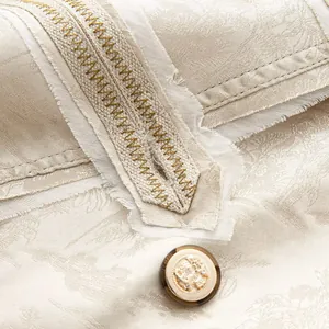 Makrodetail eines beigen Jacquard-Blazers mit gewebtem Besatz und Wappenknopf-Verzierung