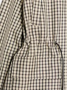 Détail rapproché d'une veste à carreaux vintage avec taille à cordon et surpiqûres