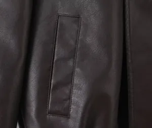 Detalle macro de chaqueta de cuero marrón oscuro con textura de grano y bolsillo
