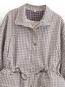 Détail d'une veste à carreaux vintage avec col montant et taille à cordon de serrage.