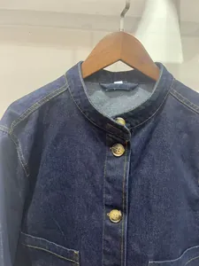 Detail van de opstaande kraag en knopen van een donkerblauw twill denim jasje voor dames