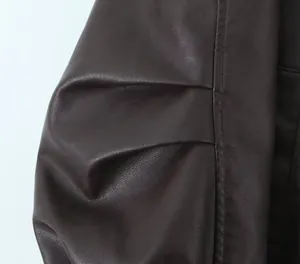 Detalle macro de manga plisada en chaqueta de cuero sintético marrón oscuro vintage.