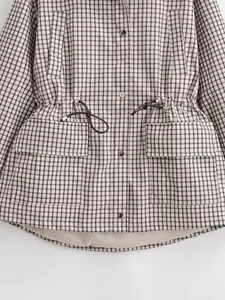 Vue détaillée d'une veste à carreaux vintage avec taille à cordon et poches à boutons.