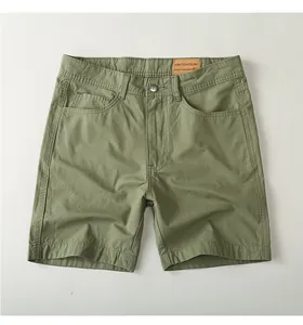 Detailed view of olive green cotton cargo shorts showing fabric texture and leather patch.