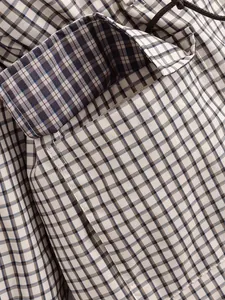 Macro d'une veste vintage à carreaux montrant les coutures et le cordon de serrage.