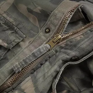 Close-up detail of vintage brass zipper on rugged American retro camouflage workwear jacket