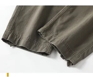 Detailed close-up showing the double-stitched hem on olive green retro cotton cargo pants.