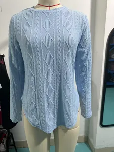 Detailed view of light blue round neck T-shirt with textured diamond pattern and curved hem