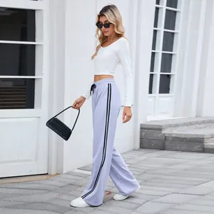 Vue latérale d'un pantalon de jogging gris large avec des bandes latérales noires