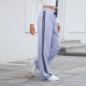 Détail du pantalon de jogging large avec des bandes latérales noires et cordon