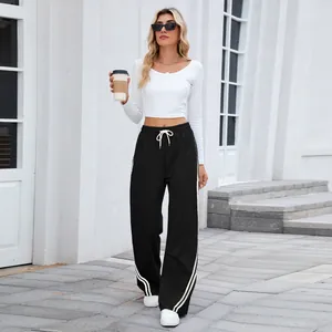 Femme stylée portant un pantalon de jogging noir large avec bandes latérales blanches