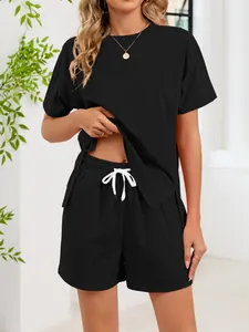 Woman in black two-piece lounge set featuring drawstring shorts and a split-hem t-shirt