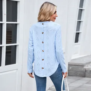 Detailed back view of a light blue knit top featuring decorative buttons and a hollow-out pattern.
