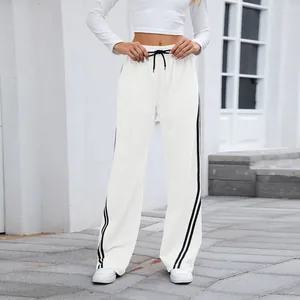 Vue complète du pantalon de jogging blanc ample à jambes larges avec bandes latérales noires