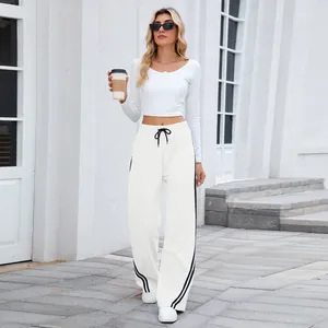 Mannequin portant un pantalon large blanc avec des rayures latérales et crop top assorti