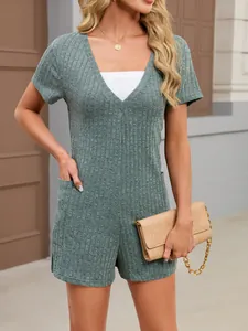 Detail of green ribbed V-neck short sleeve romper with side pocket and beige clutch