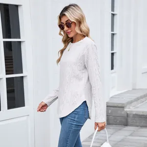 Detail view of a white crewneck knit top featuring diamond patterns and a stylish curved hem.