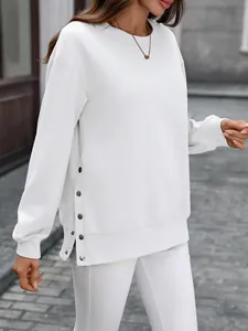 Detail eines weißen Rundhals-Sweatshirts mit dekorativen Seitenknöpfen und Schlitzsaum.