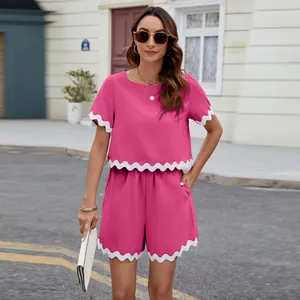 Two-piece pink short-sleeve top and shorts set with decorative white wavy trim.