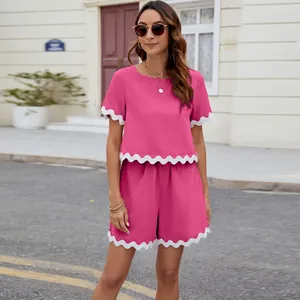 Detail view of pink two-piece set with white scalloped trim on sleeves and hem