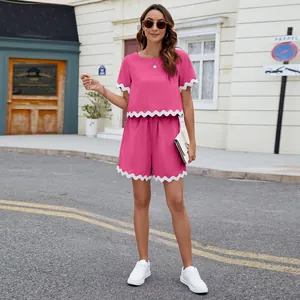 Two-piece pink set with scalloped white trim on top and shorts in outdoor street scene