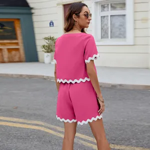 Detail shot of pink short-sleeve top and shorts set with white scalloped trim edges.