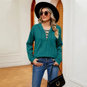 Modelo con sudadera con capucha verde azulado con cordones, sombrero negro y gafas.