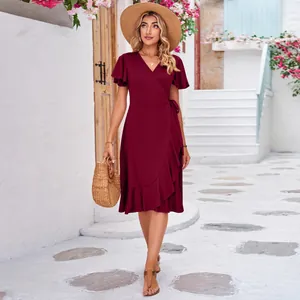 Detail view of a burgundy V-neck wrap dress with ruffled hem and short sleeves.