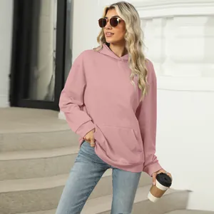 Stylish woman wearing a dusty pink oversized hoodie with kangaroo pocket on city steps