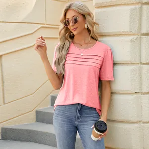 Close-up of a pink pleated U-neck t-shirt worn by a model in a casual setting.