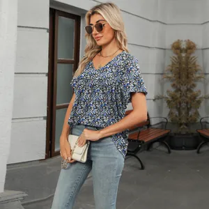 Blusa floral con cuello en V y textura plisada en un entorno urbano al aire libre.