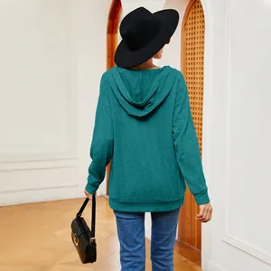 Vista trasera de una sudadera con capucha texturizada para mujer caminando por un arco