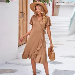 Detailed shot of a brown V-neck wrap dress with ruffled hem in a summer street setting