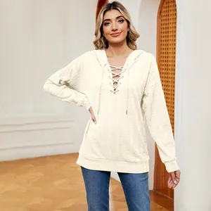 Detalle de sudadera con capucha crema con cordones y tejido texturizado