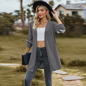 Stylish grey long cardigan with white sleeve stripes shown in an outdoor lifestyle setting.