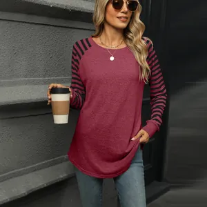 Casual burgundy women's long sleeve tee with striped sleeves and curved hem on model