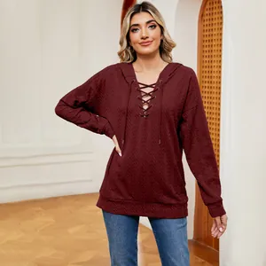 Primer plano de una sudadera con capucha granate con cordones y detalle de tela rugosa