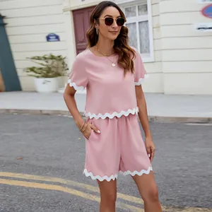 Elegant pink two-piece women's set featuring white scalloped trim, short sleeve top and shorts.